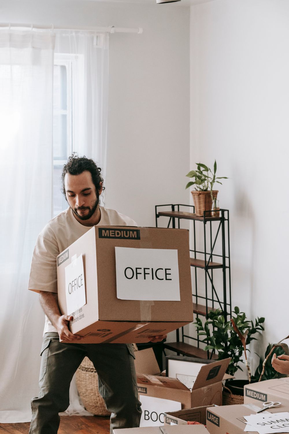 Persona cargando una caja marcada como oficina durante una mudanza de negocio
