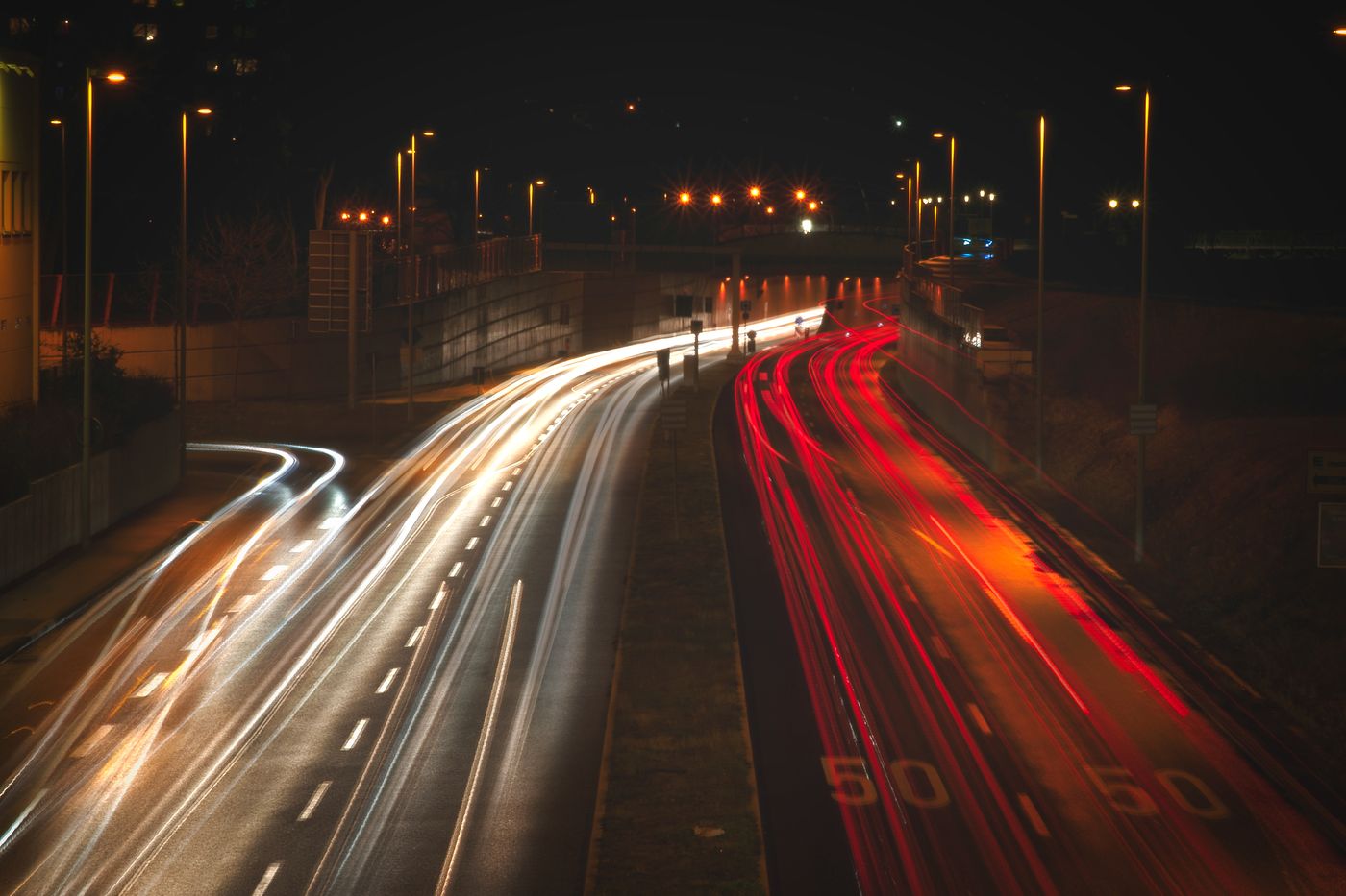 Estelas de luz roja y blanca de vehículos en una carretera de noche